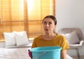 Young woman collecting leaking water from ceiling in bedroom, space for text. Time to call roof repair service Royalty Free Stock Photo