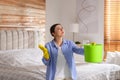 Young woman collecting leaking water from ceiling in bedroom. Time to call roof repair service Royalty Free Stock Photo