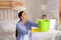 Young woman collecting leaking water from ceiling in bedroom. Time to call roof repair service Royalty Free Stock Photo