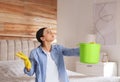 Young woman collecting leaking water from ceiling in bedroom. Time to call roof repair service Royalty Free Stock Photo