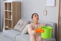 Young woman collecting leaking water from ceiling at home, space for text. Time to call roof service Royalty Free Stock Photo