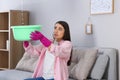 Young woman collecting leaking water from ceiling at home. Time to call roof repair service Royalty Free Stock Photo