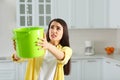 Young woman collecting leaking water from ceiling in kitchen, space for text. Time to call roof repair service Royalty Free Stock Photo