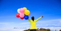 Woman with colorful balloons running on mountain peak