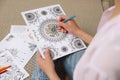 Young woman coloring antistress page on floor, closeup