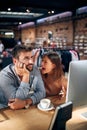 Blurred faces of young man and woman colleagues talking in front of table with desktop computer, in clothing store Royalty Free Stock Photo