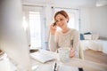 A young woman with computer and smartphone indoors, working in a home office. Royalty Free Stock Photo