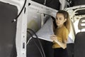 Young woman concentrated looking to the self adhesive rubber insulation in a camper van convertion Royalty Free Stock Photo