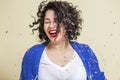 A young woman in confetti laughs and dances. Beautiful emotional curly brunette in a white T-shirt, blue sweater and jeans. Royalty Free Stock Photo