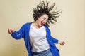 A young woman in confetti laughs and dances. Beautiful emotional curly brunette in a white T-shirt, blue sweater and jeans. Royalty Free Stock Photo