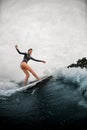 Young woman confidently stands on the wake surf board and rides the wave. Royalty Free Stock Photo