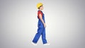 Young woman construction worker in yellow hardhat walking on gradient background. Royalty Free Stock Photo