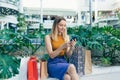 Young woman consumer in the mall browses chat and uses using a smartphone. female standing with a mobile phone in her hands in Royalty Free Stock Photo