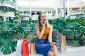 Young woman consumer in the mall browses chat and uses using a smartphone. female standing with a mobile phone in her hands in Royalty Free Stock Photo