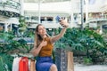 Young woman consumer in the mall browses chat and uses using a smartphone. female standing with a mobile phone in her hands in Royalty Free Stock Photo