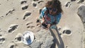 Young brunette woman in sunglasses controls piloting drone copter using console holding phone at ocean beach. Smart girl