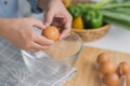 Young woman cooking in a bright kitchen, hand made cracked fresh egg yolks dripping into the bowl. Preparing ingredients for