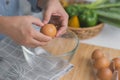 Young woman cooking in a bright kitchen, hand made cracked fresh egg yolks dripping into the bowl. Preparing ingredients for