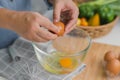 Young woman cooking in a bright kitchen, hand made cracked fresh egg yolks dripping into the bowl. Preparing ingredients for