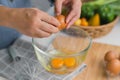 Young woman cooking in a bright kitchen, hand made cracked fresh egg yolks dripping into the bowl. Preparing ingredients for