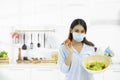 Young Woman Cooking delicious food in the kitchen and wearing face protection mask to anti saliva, cough. Stay at home during the