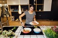 Young woman cooking a healthy meal in home kitchen.Making breakfast on kitchen island standing by induction hob.Preparing fresh