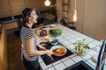 Young woman cooking a healthy meal in home kitchen.Making dinner on kitchen island standing by induction hob.Preparing fresh Royalty Free Stock Photo