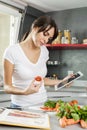 Young woman cooking at home using digital tablet for recipe Royalty Free Stock Photo