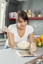 Young woman cooking at home using digital tablet for recipe Royalty Free Stock Photo