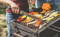 Young woman cooking organic vegetables at barbecue dinner outdoor - Couple grilling peppers and aubergines for vegan bbq -