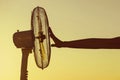 Young Woman cooling herself during hot weather in front of fan on a blue sunset sky background Royalty Free Stock Photo