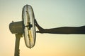 Young Woman cooling herself during hot weather in front of fan on a blue sunset sky background Royalty Free Stock Photo