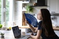 Young woman cools herself with handheld waver at home