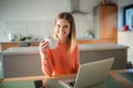 Young woman with cop of coffee using laptop smiling Royalty Free Stock Photo