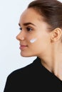 Young woman with cosmetic cream on a clean fresh face.Beautiful model applying cosmetic cream treatment on her face on white backg Royalty Free Stock Photo