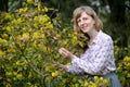 The young woman costs among the blossoming bushes of a trailing mahonia