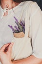 Young woman in cotton clothes carries textile bag and lavender in paper as a concept of natural material, ecological production