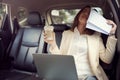 Young woman cover her face with a paperwork while she working and recive bad news about her job in her car