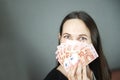 Young woman covering her face with fan of euro money over grey background Royalty Free Stock Photo