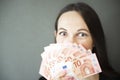 Young woman covering her face with fan of euro money over grey background Royalty Free Stock Photo