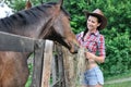 Young woman in cowgirl style feeding horse Royalty Free Stock Photo