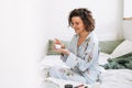 Young woman in cozy blue pajamas using cosmetic cream in hands at home Royalty Free Stock Photo