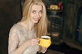 Young woman in a cozy interior of Christmas. A girl is sitting with a yellow mug under a Christmas tree among many presents. Prepa Royalty Free Stock Photo