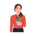 Young woman in cozy room holds pot with a plant in her hands. Concept of growing and caring house plants. Gardener takes care of Royalty Free Stock Photo