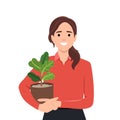 Young woman in cozy room holds pot with a plant in her hands. Concept of growing and caring house plants. Gardener takes care of Royalty Free Stock Photo