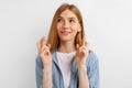 Young woman with crossed fingers and wishing all the best, over white background Royalty Free Stock Photo