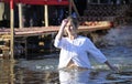 Young woman crosses herself plunging into icy water during the feast Epiphany on the Dnieper River