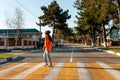 A young woman crosses a pedestrian crossing. Empty road and streets. Sunny. Concept of traffic rules Royalty Free Stock Photo