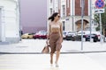 A young woman crosses the road in the city. Beautiful stylish brunette with a bag Royalty Free Stock Photo