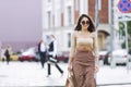 A young woman crosses the road in the city. Smiling beautiful brunette